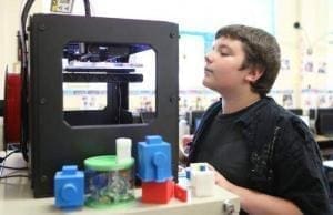Menino olhando impressora 3D Makerbot funcionando dentro de uma escola. Continue lendo nosso post.