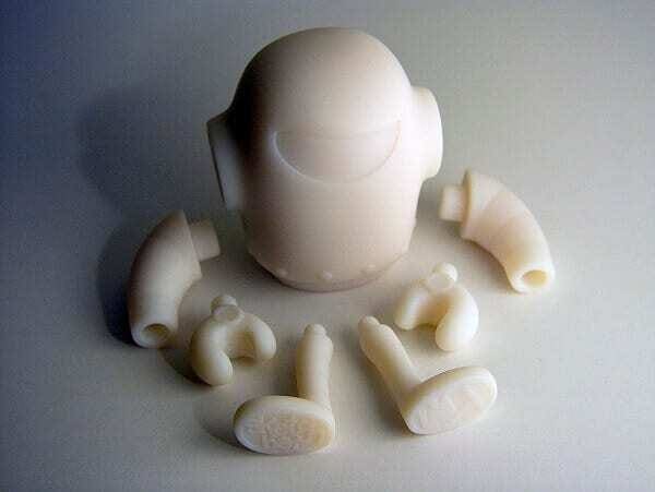 Modelo de boneco em forma de robozinho impresso em 3D na cor branca.