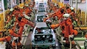 Linha de produção de indústria automotiva. Automóveis sendo feitos através de máquinas e não mais operários. Máquinas de cor laranja.